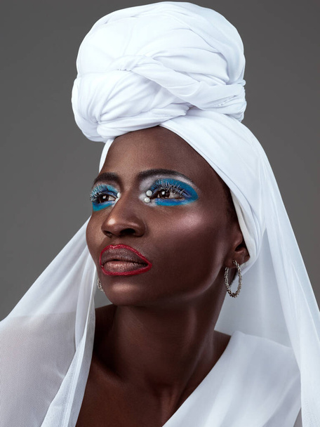 Stil, der traditionsreich ist. Studioaufnahme einer attraktiven jungen Frau, die in traditioneller afrikanischer Kleidung vor grauem Hintergrund posiert - Foto, Bild