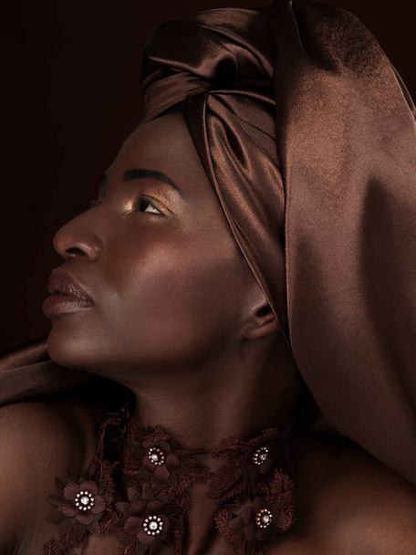 Το στυλ καμπής του κεφαλιού. Στιγμιότυπο από μια ελκυστική νεαρή γυναίκα που ποζάρει με παραδοσιακή αφρικανική ενδυμασία σε μαύρο φόντο - Φωτογραφία, εικόνα
