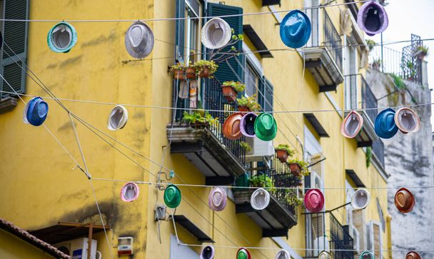 Sombreros de colores colgados entre bloques en un alambre en Nápoles Italia - Foto, imagen