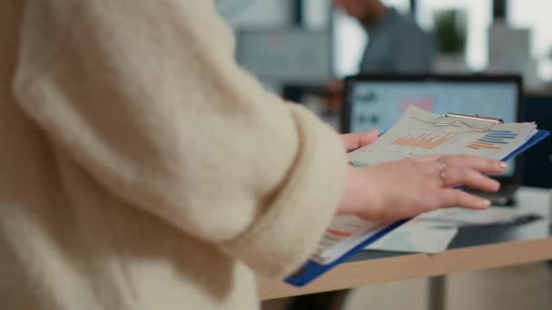 Closeup of woman hands holding clipboard with papers looking at pie chart and business profit data in startup office. Focused employee analyzing key performance indicators reading turnover statistics. - Кадры, видео