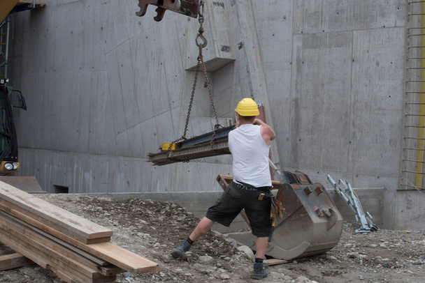Trabalhador com guindaste de construção com carga pesada no lado da construção - Foto, Imagem