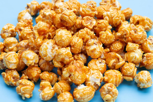 Miele caramello popcorn su sfondo blu. - Foto, immagini