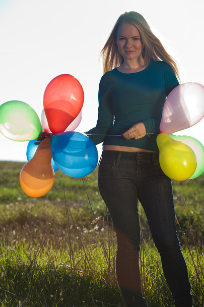Young beautiful woman with balloons into the field against the s - Foto, Bild