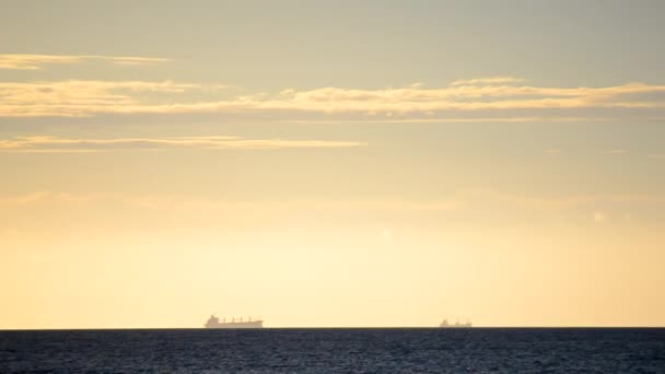 Zaman ayarlı. Denizdeki ufuk çizgisinde tanker tankerlerinin silueti ve gün batımında sarı mavi gökyüzünde hızlı hareket eden bulutlar. Deniz manzarası, deniz manzarası. Ulaşım. Doğal arkaplan - Video, Çekim