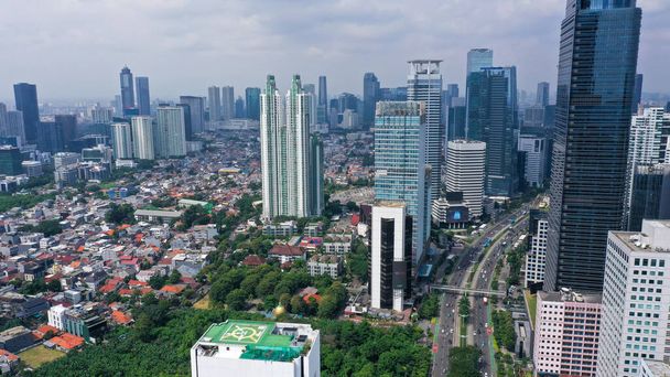 ジャカルタの中央ビジネス地区、ジャカルタ中心部のビジネス地区に位置し、インドネシアの青い空の下で近代的なオフィスビルの Indonesiaaerial ビューにおける事務所ビルの空撮. - 写真・画像