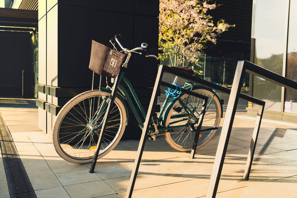 Modern bicycle parked on city street. Business centre district. Exterior design. Vintage ladies cruiser bicycle parked on downtown. Female bike in modern city centre architecture  - Fotoğraf, Görsel