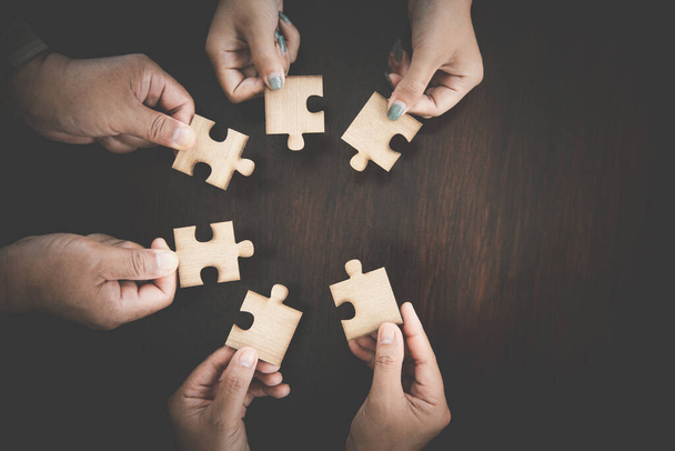 Hand holding jigsaw puzzles, Business partnership concept. hands of businessmen connect puzzle pieces on dark background. Business concept idea, teamwork, cooperation, partnership, creative. - 写真・画像
