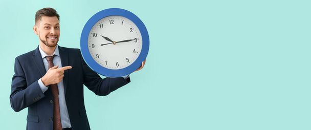 Businessman with big clock on light blue background. Time management concept - Zdjęcie, obraz