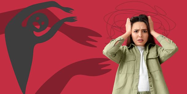 Scared young woman having panic attack and monsters on red background - Photo, Image