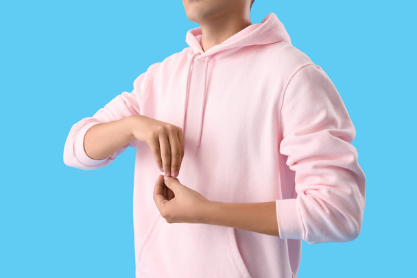 Joven con capucha rosa meditando sobre fondo azul, primer plano - Foto, imagen