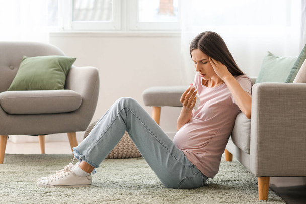 Young pregnant woman with nosebleed and tissue at home - Photo, Image