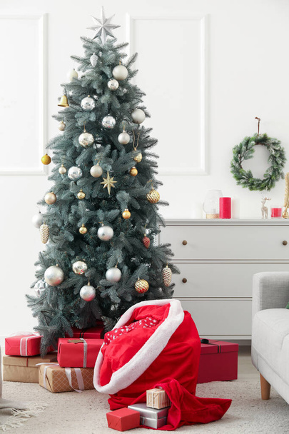 Beautiful Christmas tree and Santa bags with gifts in room - Фото, зображення