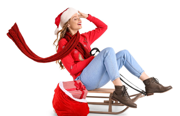 Nuori nainen Santa hattu laukku ja kelkka istuu valkoisella taustalla - Valokuva, kuva