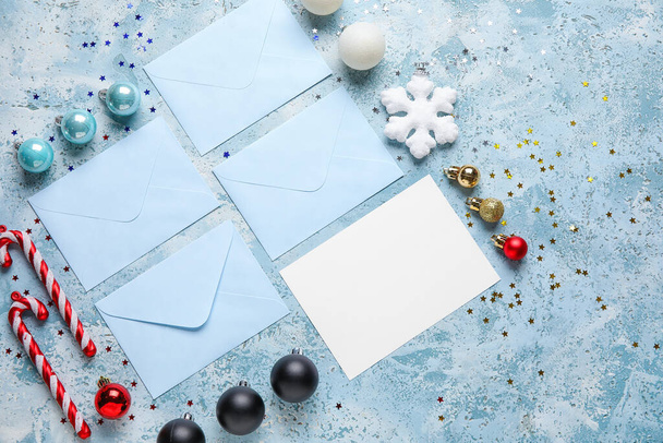 Композиція з порожньою карткою, конвертами та різдвяними прикрасами на кольоровому фоні
 - Фото, зображення