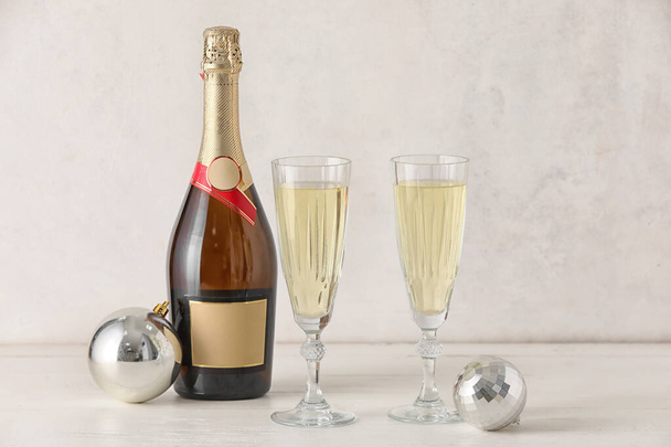 Şişe, şampanya bardakları ve açık ahşap masada Noel topları. - Fotoğraf, Görsel