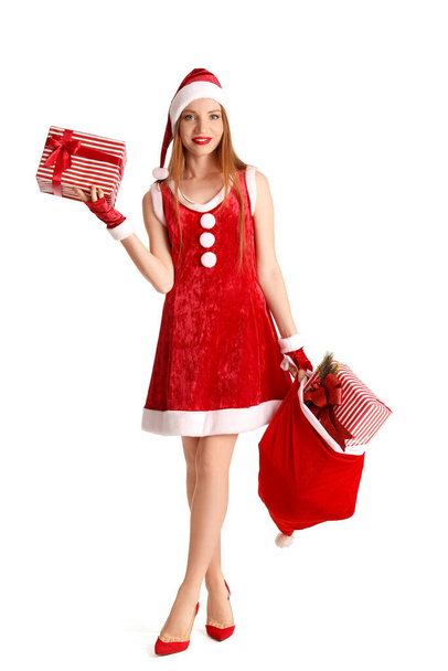 Beautiful young woman in Santa costume with bag of gifts on white background - Фото, изображение
