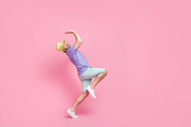 Full length photo of attractive young man lift up copyspace object shopping promo wear stylish blue look isolated on pink color background. - 写真・画像