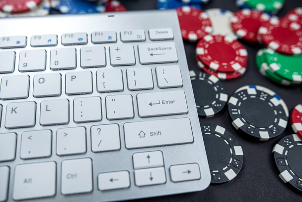 コンピュータのキーボードやノートパソコンにポーカーチップが置かれてる。孤立したギャンブルオンラインカジノのインターネット賭けの概念。ジャックポット。チップカジノ. - 写真・画像
