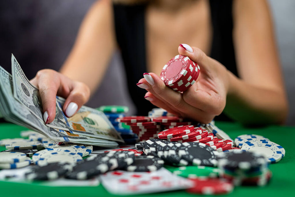 γυναίκα παίκτης μετράει μάρκες για τα χρήματα και αυξάνει το στοίχημα παίζοντας πόκερ στο καζίνο. ιδέα τζόγου. Γυναίκα και πόκερ. μια γυναίκα με φόρεμα. - Φωτογραφία, εικόνα