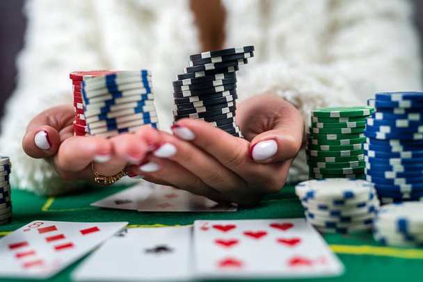 A beautiful young woman is successfully gambling in a casino at a table with cards chips and alcohol close-up. poker game woman in excitement - Photo, Image