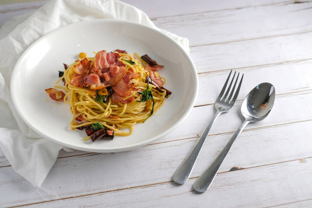 Sült spagetti szárított chilivel és ropogós szalonnával fehér tálban.. - Fotó, kép