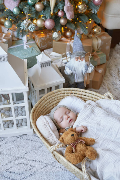 Schlafendes Baby. Das Christkind liegt in der Wiege neben dem Weihnachtsbaum. Frohe Weihnachten und ein gutes neues Jahr. - Foto, Bild