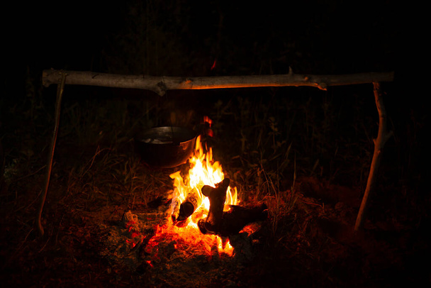 Kochen in einem Zeltlager weit weg von der Stadt, auf natürlichem Brennholz spät in der Nacht - Foto, Bild