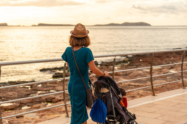 A mother watching the sunset on the Paseo de Poniente in San Antonio Abad, Ibiza Island. Balearic - Foto, Bild