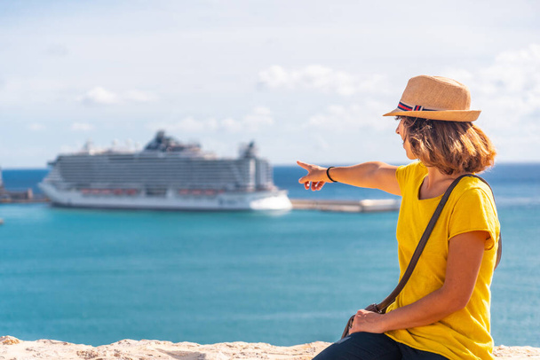 A young woman pointing on the cruise ship that she has arrived at the island of Ibiza to spend the holidays - Foto, Bild