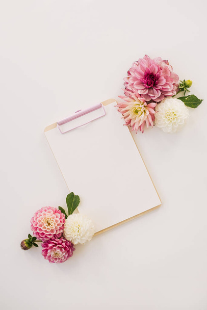Blocco appunti con spazio di copia vuoto, boccioli di fiori su tavolo rosa pastello. Spazio di lavoro estetico minimalista. Artista, modello scrittore - Foto, immagini