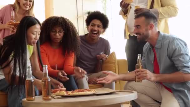 groupe multinational d'amis partagent de la nourriture et de bons rires dans un salon. - Séquence, vidéo