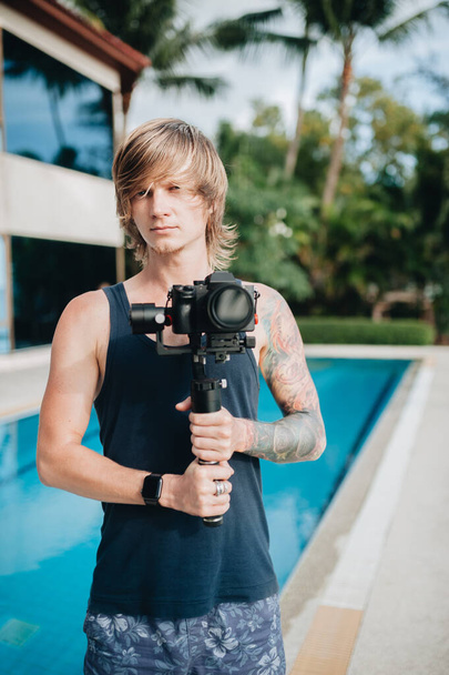 Man videographer is standing outdoors with his camera and gimbal. Selective focus - Fotó, kép
