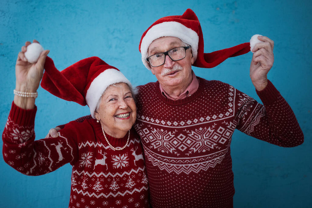 Portrait of happy senior couple with Santa Claus hats, studio shoot. - Photo, image