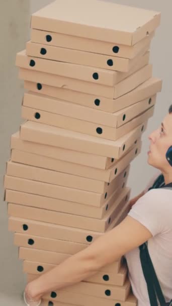 Függőleges videó: Ügyetlen élelmiszer futár próbál elkapni csökkenő pizza dobozok, jár ijedt és fut az ügyfél elől, miután leejtette gyorséttermi szállítási étkezés. Félelmetes fuvarozó rossz szolgálattal - Felvétel, videó
