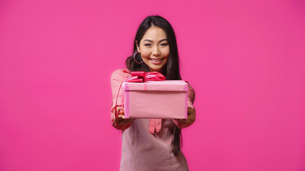 щаслива молода азіатська жінка дає загорнутий подарунок ізольовано на рожевому
  - Фото, зображення