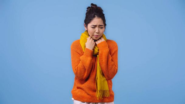 malato asiatico donna in arancio maglione e sciarpa sentirsi male isolato su blu  - Foto, immagini