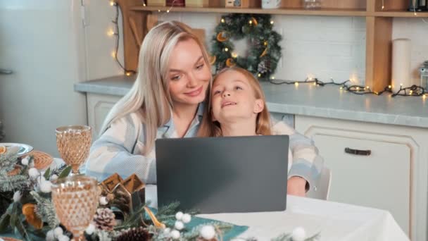 Onnellinen kaunis vaalea äiti siniset silmät ja tytär katsomassa videota kannettavan tietokoneen tehdä verkko-ostoksia, jouluaatto myynti. Viettää laatuaikaa perheen kanssa joululomalla, uusi vuosi käsite - Materiaali, video