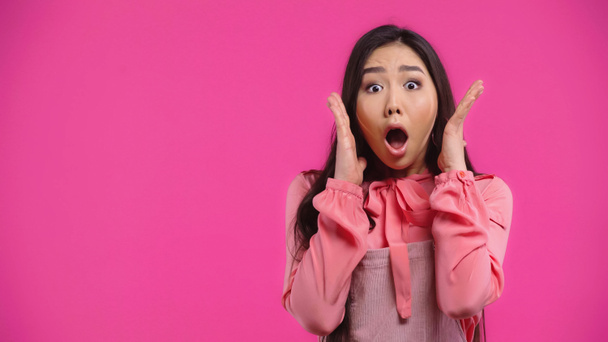 wstrząśnięta i młoda Azjatka z otwartymi ustami gestykulująca na różowo - Zdjęcie, obraz