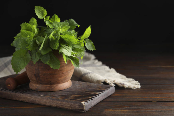 Mortar fresh green lemon balm leaves on wooden table. Space for text - Photo, Image