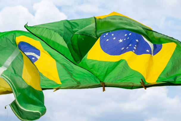 Kilka brazylijskich flag, machających na wietrze, na sznurze ubrań z zachmurzonym niebem w tle. - Zdjęcie, obraz