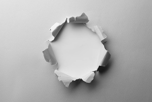 Hole in white paper on light background - Photo, image