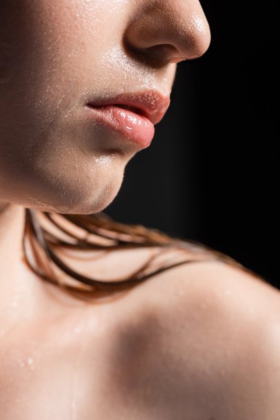 Close up άποψη της γυναίκας με υγρό δέρμα και τα χείλη απομονώνονται σε μαύρο - Φωτογραφία, εικόνα