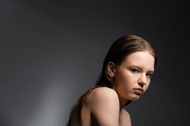 Fair haired model with wet shoulders looking at camera on grey background  - Fotografie, Obrázek
