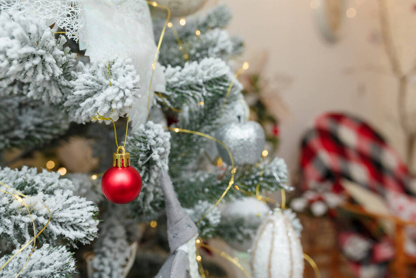 Рождественская елка, покрытая искусственным снегом и луковицами на фоне камина. Ветви елки с игрушками на Новый год - Фото, изображение