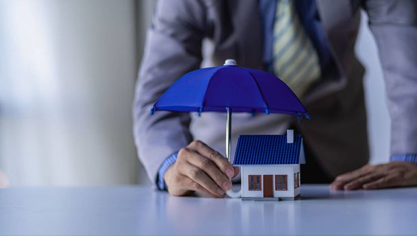 бізнесмен, розповсюджуючи блакитну парасольку для будинку Нерухомість, страхування та концепції власності
 - Фото, зображення