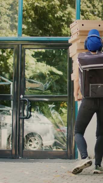 Vidéo verticale : Pizzeria courrier féminin déposer des boîtes de pizza pile à la porte d'entrée du client, étant maladroit et en cours d'exécution. Mauvais service de livraison, employé du restaurant à emporter essayant d'attraper des paquets en chute libre - Séquence, vidéo