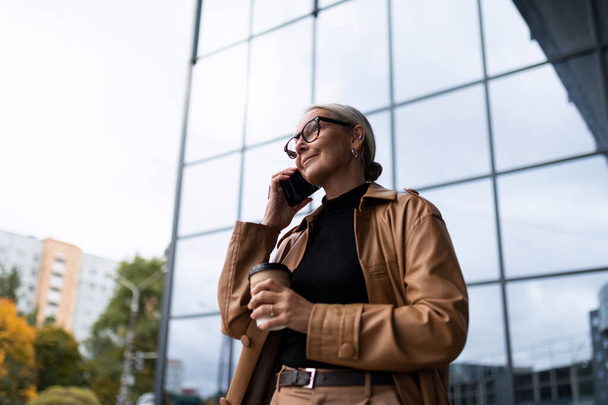 stylish adult European businesswoman on the background of the glass facade of the office. - Photo, Image