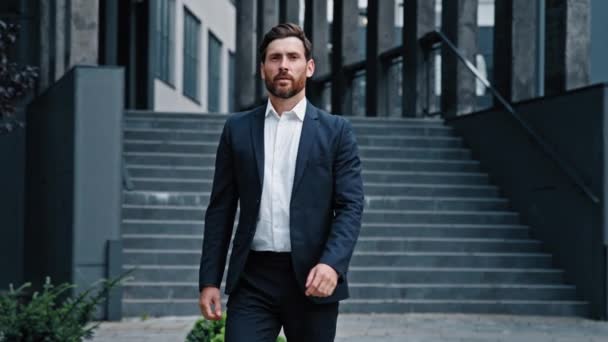 Úspěšný sebevědomý stylový pohledný vousatý kavkazský podnikatel kráčející po ulici proti pozadí kancelář budova vážné zamyšlený muž ve formálním obleku profesionální manažer vůdce procházky venku - Záběry, video