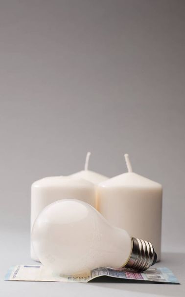 ampoule sur le dessus de 20 billets en euros avec des bougies, fond gris - Photo, image