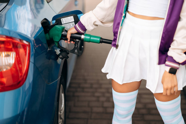 Wesoła młoda kobieta brunetka napełniająca samochód paliwem na stacji benzynowej - Zdjęcie, obraz